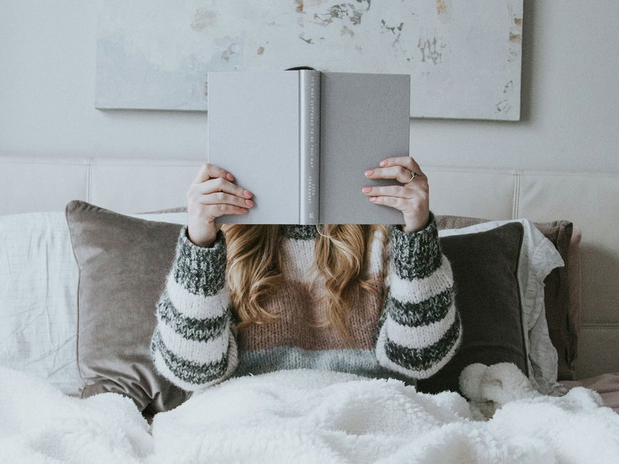 Frau mit Buch im Bett