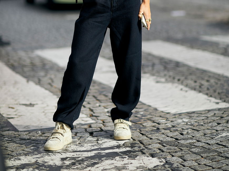 Frau mit schwarzem Outfit und Sneakern