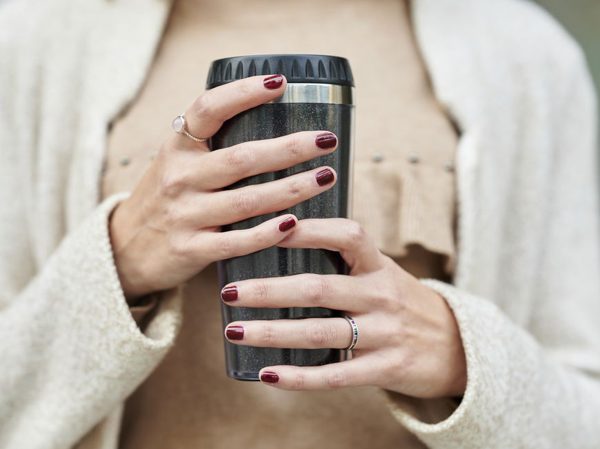 Frau hält einen Thermobecher in der Hand.