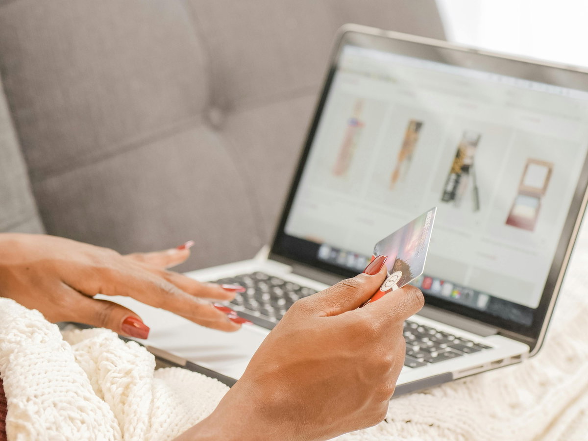 Frau vor dem Laptop mit einer Kreditkarte in der Hand