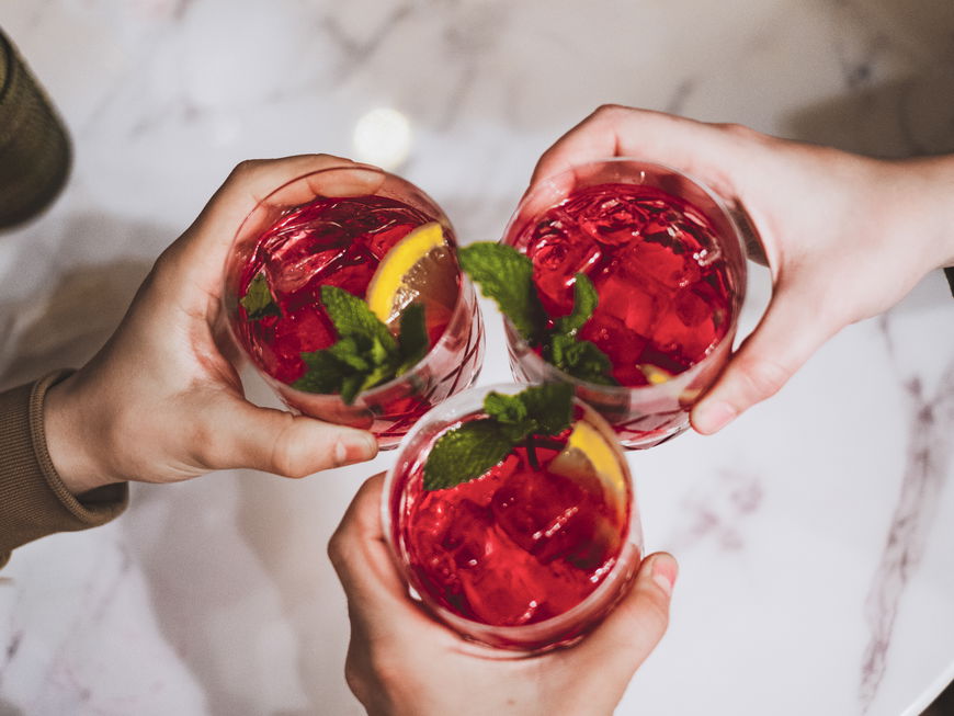 Freundesgruppe stößt mit roten Cocktails an