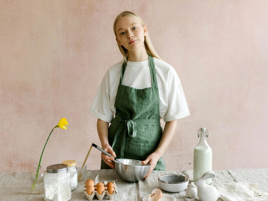 Frau mit grüner Schürze backt Kuchen