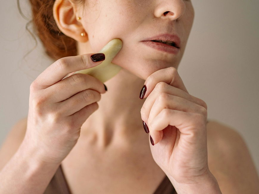 Frau benutzt Beauty Tool Gua Sha Stein