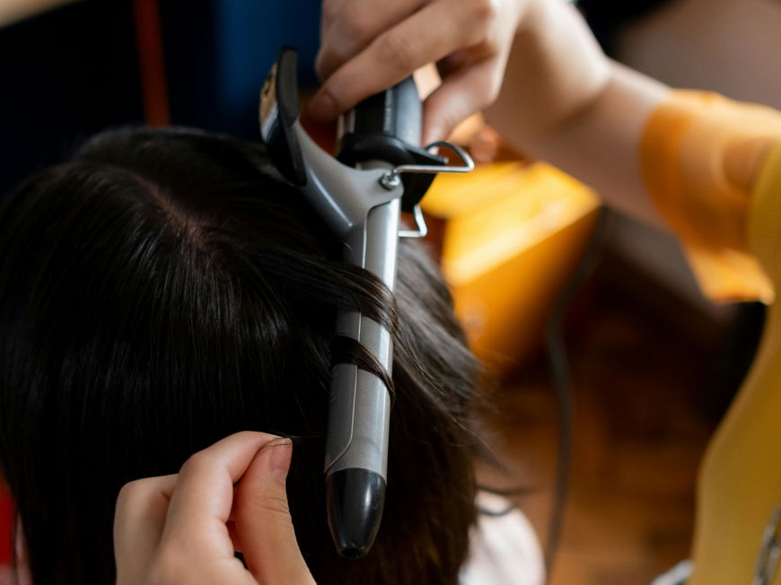 Frau lockt Haare mit Lockenstab