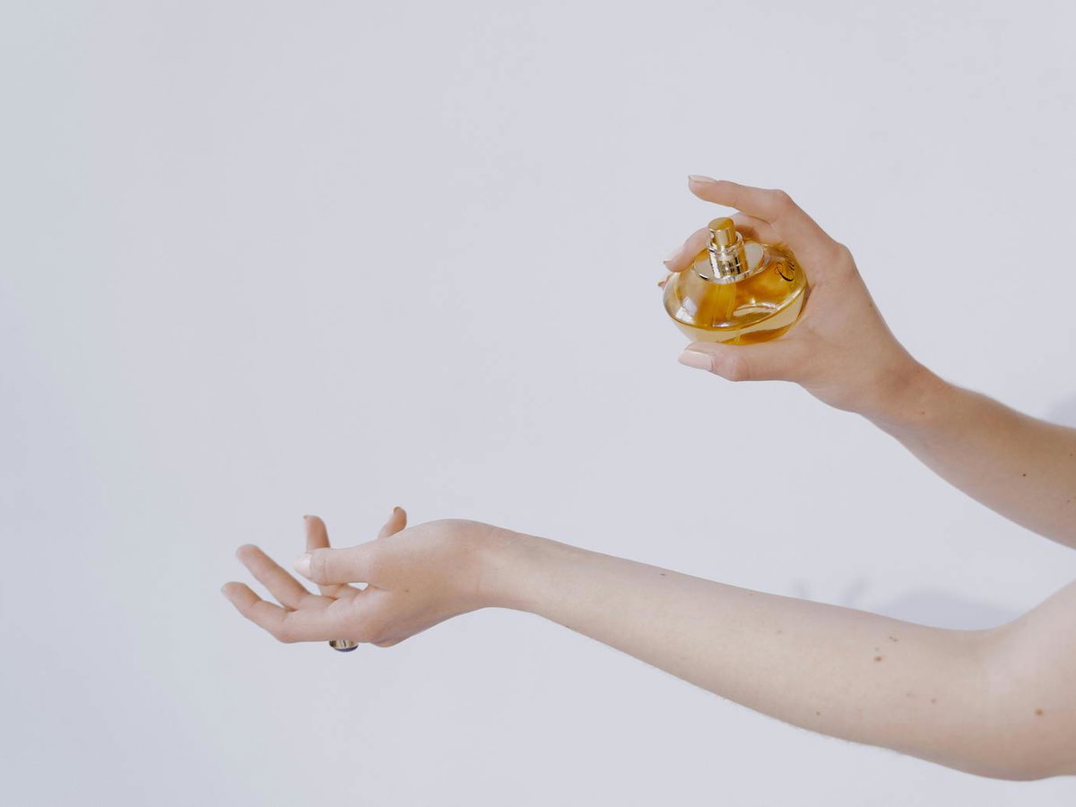 Frau sprüht Parfum auf ihren Unterarm