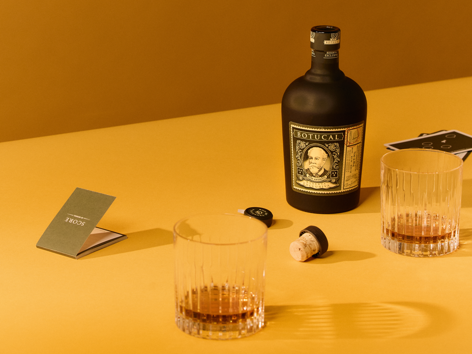Botucal Reserva Exklusiva Rumflasche mit zwei Gläsern auf einem Tisch – ideal für elegante Drinks wie den Old Fashioned.