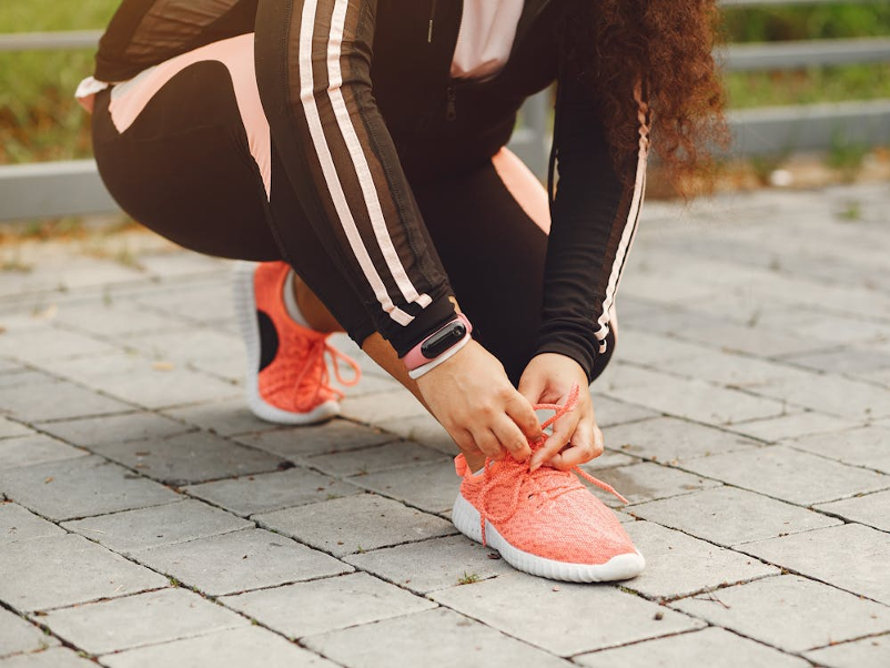 Eine Frau bindet sich ihren Sportschuh fest