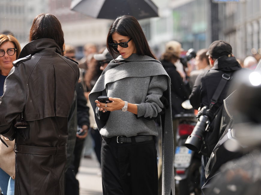 Frau mit grauem Outfit schaut auf ihr Handy