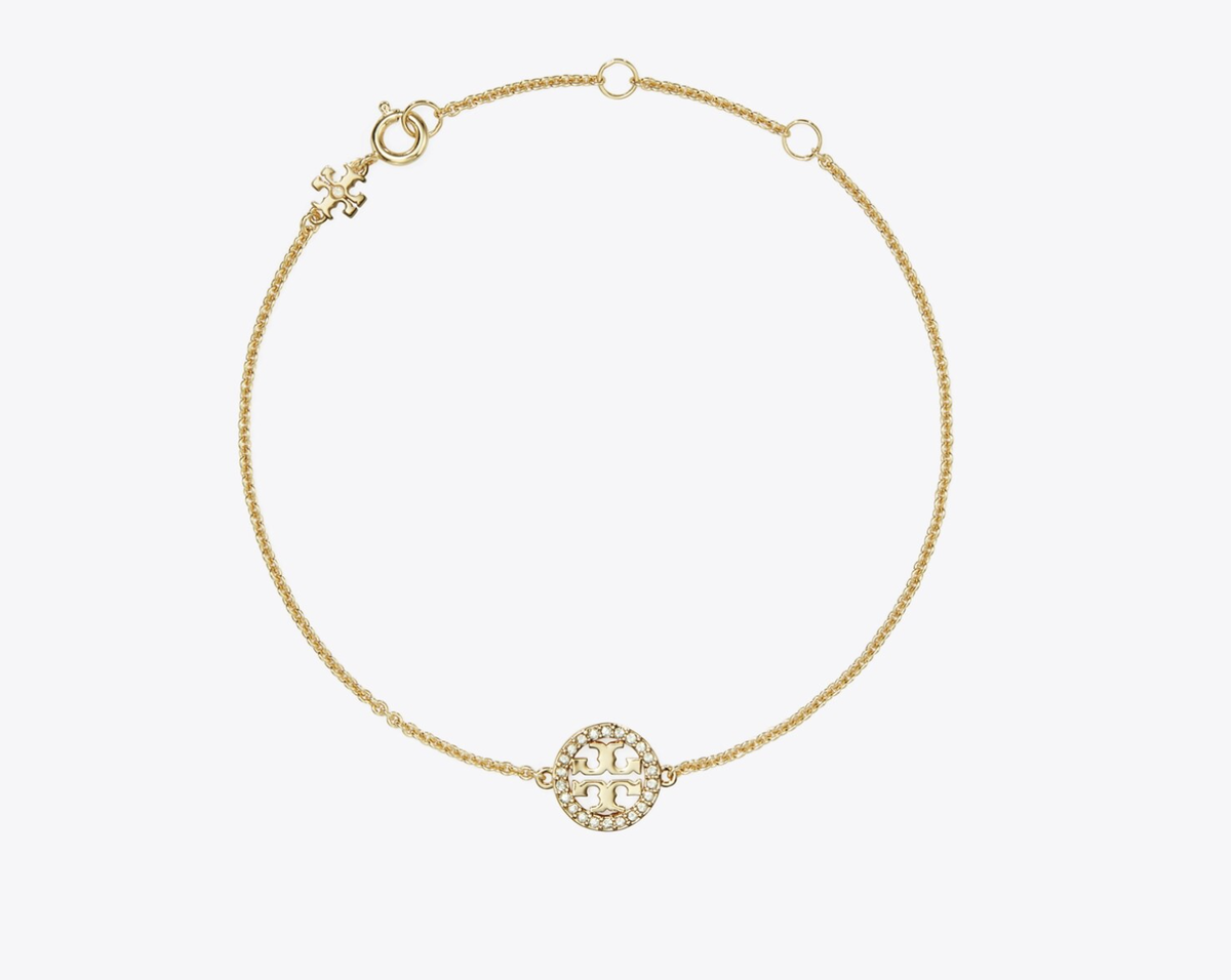Ein Hauch von Glamour für das Handgelenk: Dieses elegante Gliederarmband von Tory Burch besticht durch sein zeitloses Design und funkelnde Pave-Details. Ein hochwertiges Schmuckstück, das jedes Outfit aufwertet und deine Mutter jeden Tag strahlen lässt.