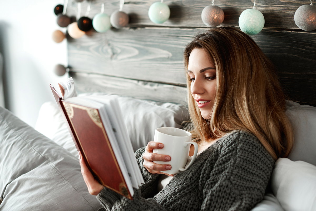 Frau liest Buch im Bett