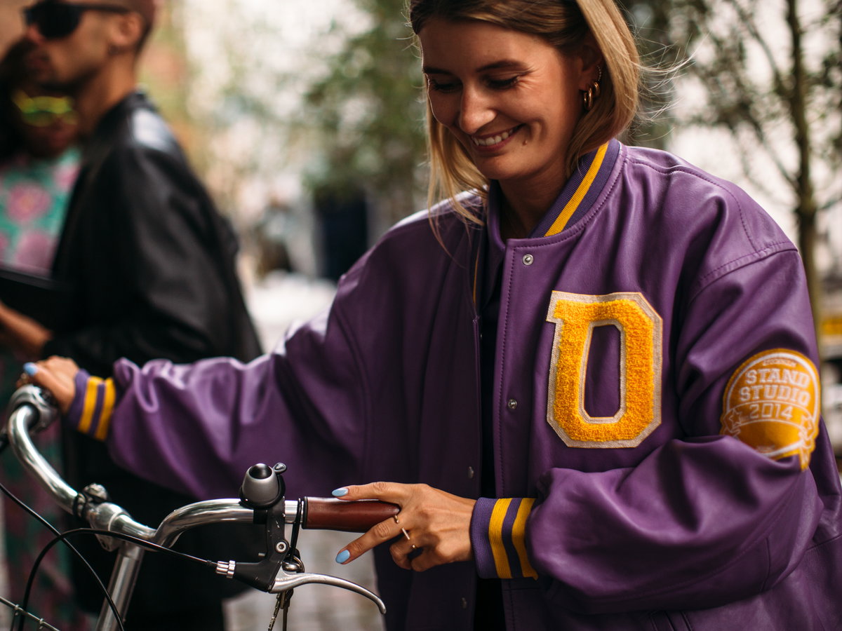 Frau mit einer lilafarbenen Collegejacke aus Leder