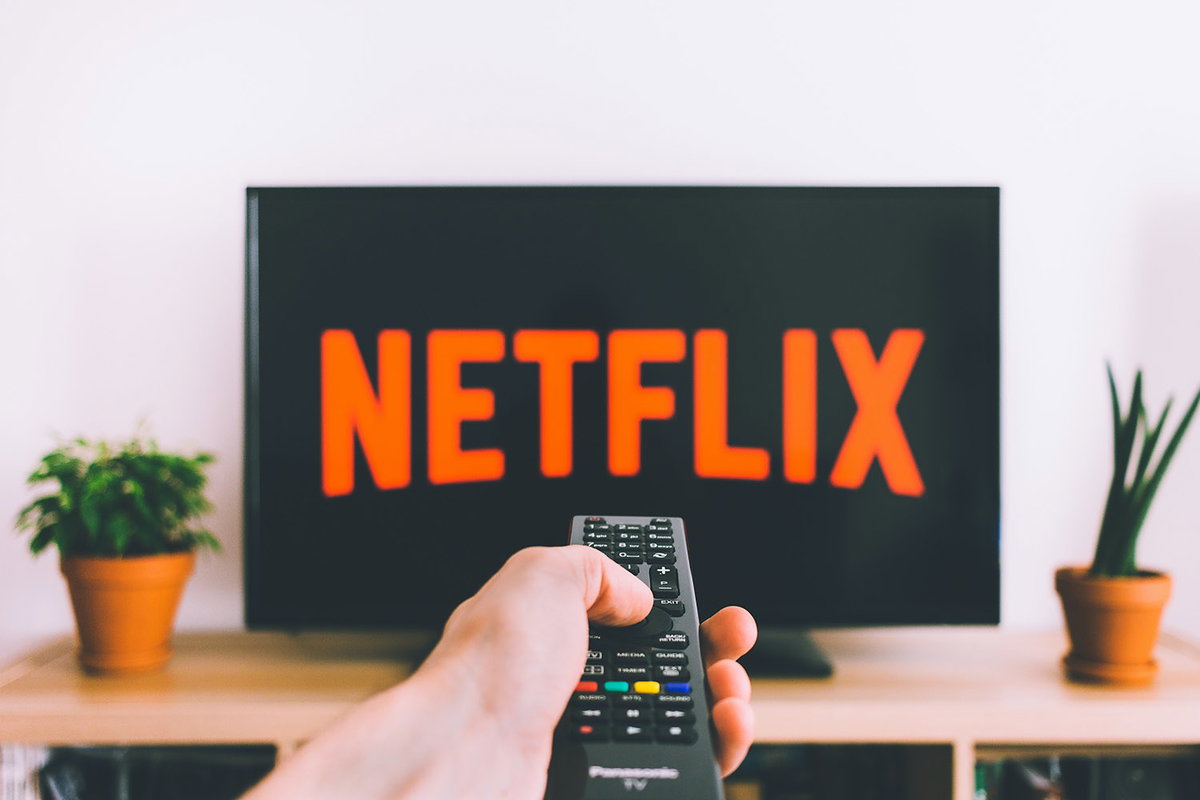 Person schaut Netflix und bedient die Fernbedienung