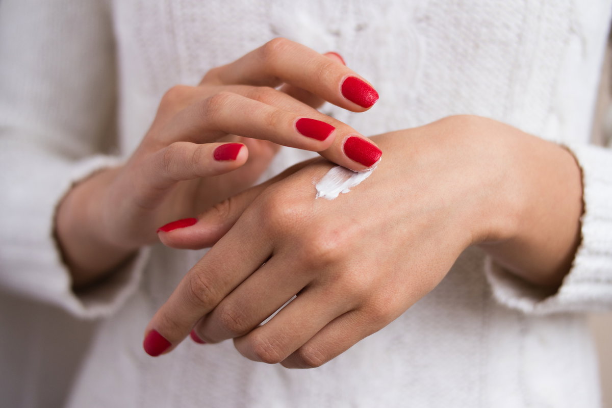 Frau trägt sich eine pflegende Handcreme auf