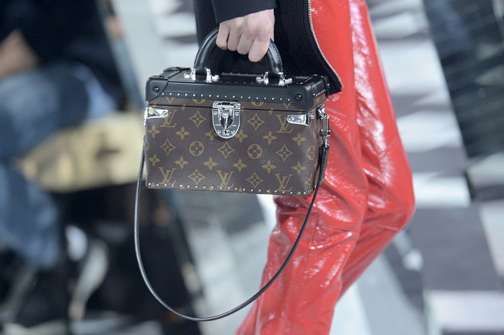 Eine Frau trägt eine Tasche im Koffer-Stil mit dem Louis Vuitton Monogram-Muster