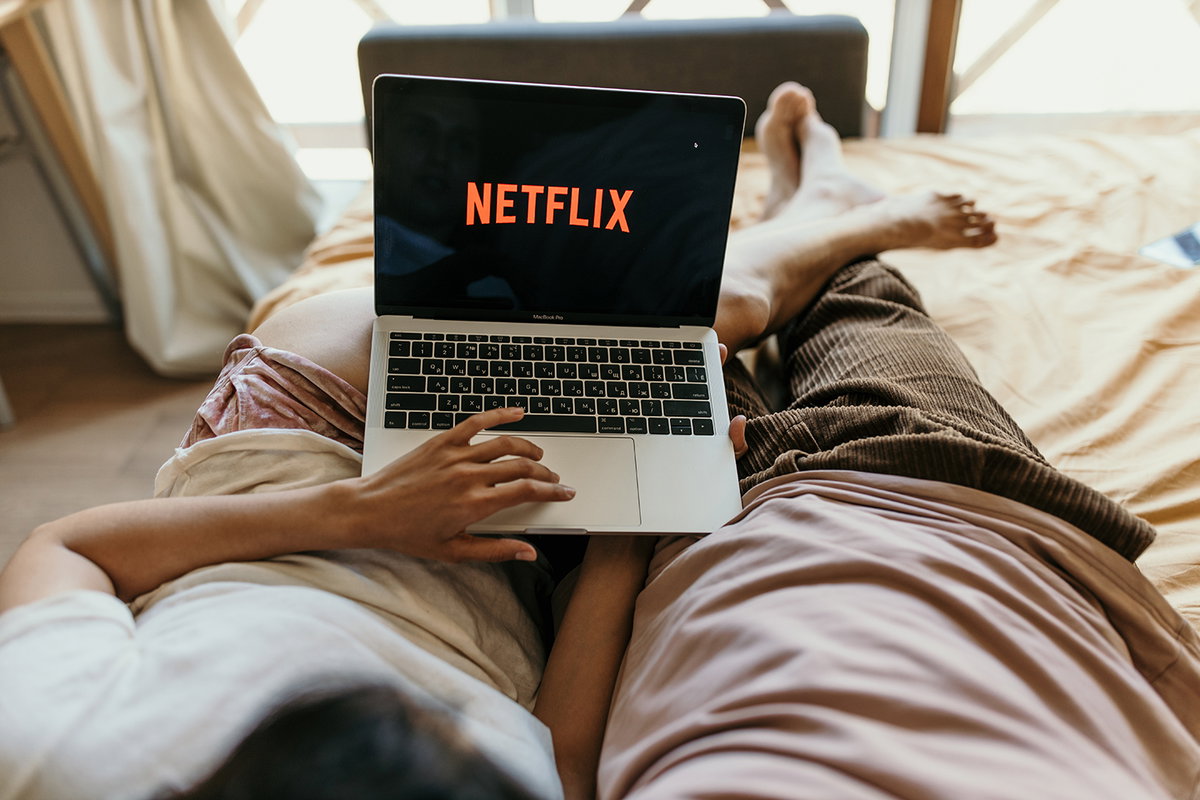 Paar liegt im Bett mit einem Laptop